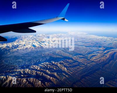 Schöner Blick auf die Erde aus dem Bullauge eines Flugzeugs. Die Berge des Iran. Stockfoto