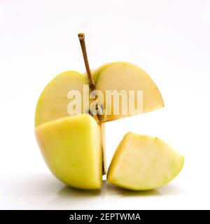 Ein einzigartig geschliffener grüner Apfel mit frischem Aussehen, der kunstvoll vor weißem Hintergrund angeordnete Scheiben zeigt Stockfoto