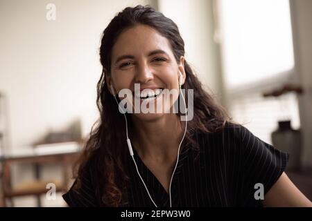 Kopfaufnahme Porträt überglücklich Frau trägt Kopfhörer lachend Kamera Stockfoto