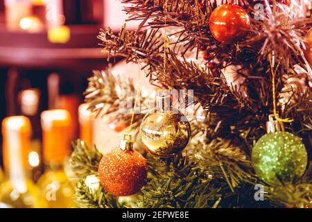 Nahaufnahme von festlich geschmückten Outdoor Weihnachtsbaum mit leuchtend roten Kugeln auf verschwommenem funkelnden Feen Hintergrund. Defokused Girlande Lichter, Bokeh eff Stockfoto