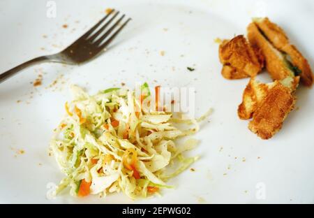 Essensreste und Gabel auf weißem Teller Stockfoto