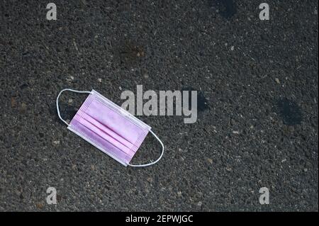Detail einer schmutzigen und gebrauchten rosa Maske für covid-19 Schutz liegt auf der Straße Stockfoto