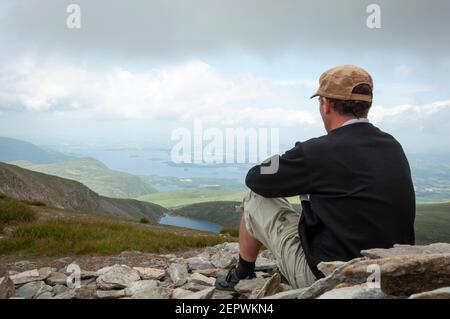 Ein alleinesischer Wanderer auf dem Mangerton Summit mit Blick auf den Devil's Punch Bowl See und das Killarney Valley beeindruckende Landschaft County Kerry, Irland Stockfoto