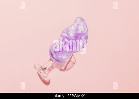 Ein Glas Wein mit kreativem violettem Getränk verschüttet auf einem rosa Hintergrund. Minimalkonzept. Stockfoto