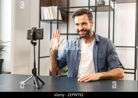 Hinter den Kulissen der jungen bärtigen Hipster männlichen Blogger vlogger Streaming Video online oder Aufzeichnung Tutorial für Social Media-Netzwerk, winken, Gruß Freunde Anhänger mit High-Five, sagen Hallo Stockfoto