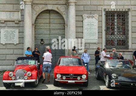 Oldtimer-Rallye mit Alfa Romeo und Morgan Autos geparkt vor dem Rathaus von Sarzana mit Menschen im Sommer, La Spezia, Ligurien, Italien Stockfoto