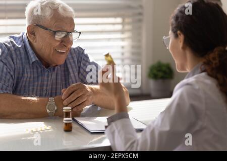 Nahaufnahme Ärztin verschreibt Medizin zu lächelnden älteren Mann Stockfoto