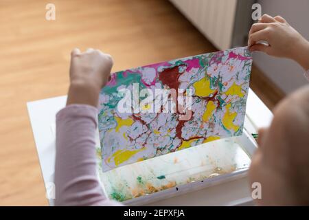 Prozess der Erstellung der Zeichnung Ebru. Kind zeichnet mit Farben auf Wasser Stockfoto