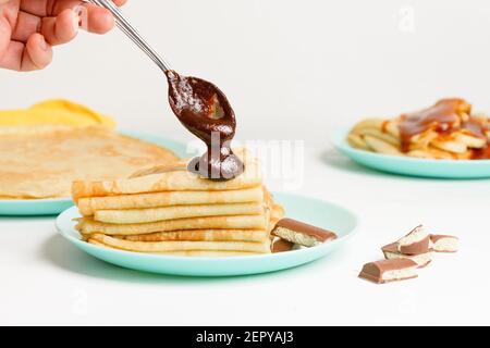 Blini Pfannkuchen mit Schokolade, Nahaufnahme auf einem blauen Teller auf einem hellen Hintergrund. Traditionelle russische Feiertag ist ein Symbol des Frühlings und süßes Dessert. Stockfoto