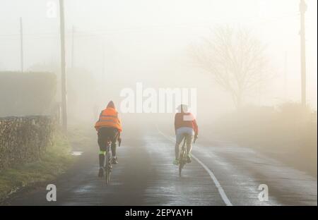 Crosshaven, Cork, Irland. 28th. Februar 2021. Zwei Männer, die am frühen Morgen bei Goats Cross, Crosshaven, Co. Cork, Irland, eine Radtour bei starkem Nebel Unternehmen. - Credit; David Creedon / Alamy Live News Stockfoto