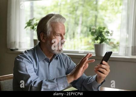 Fokussierter alter grauhaariger Mann mit App auf dem Smartphone Stockfoto