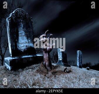 Eine Zombie Hand steigt aus einem Grab in einem gespenstischen alten Friedhof. Stockfoto