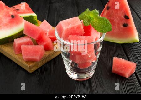 Eiswürfel mit Wassermelone im Glas auf dem schwarzen Holzoberfläche Stockfoto