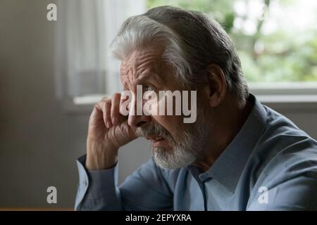 Verwirrt verärgert alter 70s-jähriger Mann, der Gesicht und Auge reibt Stockfoto