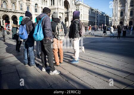 Mailand, Italien - 11. Januar 2019: Afrikanische schwarze Männer, Männer, Immigranten, die auf dem Mailänder Duomo Platz stehen, mit Touristen Stockfoto