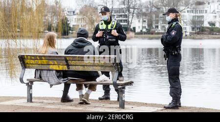 Hamburg, Deutschland. Februar 2021, 28th. Polizeibeamte wenden sich an ein Paar in der Hamburger Außenalster, weil sie auf dem Bakn keinen Mund-Nase-Schutz trugen. Seit gestern hat Hamburg eine strengere Maskenanforderung im öffentlichen Raum. Quelle: Markus Scholz/dpa/Alamy Live News Stockfoto