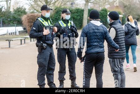 Hamburg, Deutschland. Februar 2021, 28th. Polizisten wenden sich an Wanderer rund um die Hamburger Außenalster, die sich nicht an die strenge Maskenpflicht halten. Im Falle einer Wiederholung können sie eine Geldstrafe verhängen. Quelle: Markus Scholz/dpa/Alamy Live News Stockfoto