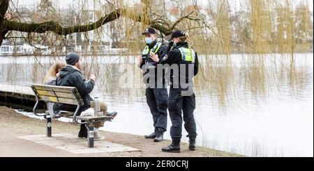 Hamburg, Deutschland. Februar 2021, 28th. Polizeibeamte wenden sich an ein Paar in der Hamburger Außenalster, weil sie auf dem Bakn keinen Mund-Nase-Schutz trugen. Seit gestern hat Hamburg eine strengere Maskenanforderung im öffentlichen Raum. Quelle: Markus Scholz/dpa/Alamy Live News Stockfoto