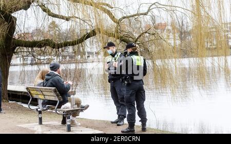 Hamburg, Deutschland. Februar 2021, 28th. Polizeibeamte wenden sich an ein Paar in der Hamburger Außenalster, weil sie auf dem Bakn keinen Mund-Nase-Schutz trugen. Seit gestern hat Hamburg eine strengere Maskenanforderung im öffentlichen Raum. Quelle: Markus Scholz/dpa/Alamy Live News Stockfoto