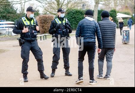 Hamburg, Deutschland. Februar 2021, 28th. Polizisten wenden sich an Wanderer rund um die Hamburger Außenalster, die sich nicht an die strenge Maskenpflicht halten. Im Falle einer Wiederholung können sie eine Geldstrafe verhängen. Quelle: Markus Scholz/dpa/Alamy Live News Stockfoto