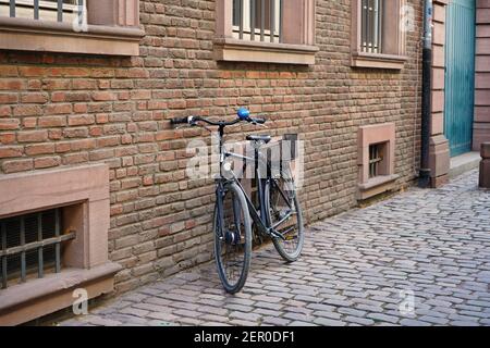 Typische alte Straße in der historischen Düsseldorfer Altstadt mit Backsteingebäude, altem Fahrrad und Kopfsteinpflaster. Stockfoto