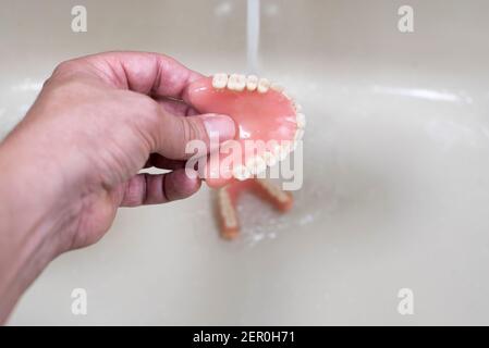 Wäsche und Reinigung der Zähne Zahnersatz im Waschbecken mit fließendem Wasser Stockfoto