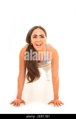 Vertikales Porträt einer jungen Frau, die eine Presse nach oben macht, isoliert auf weißem Hintergrund. Stockfoto