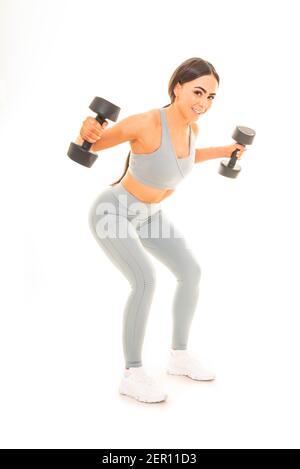 Vertikales Porträt einer jungen Frau mit Hanteln in einem Training, isoliert auf weißem Hintergrund. Stockfoto