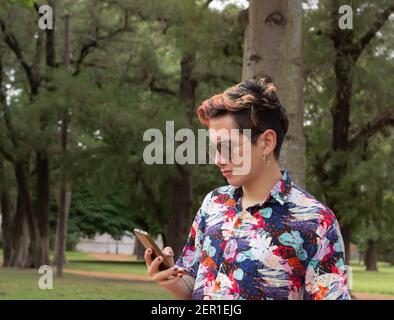 Junger Mann in einem farbigen Hemd mit einem Handy in der Hand. Stockfoto