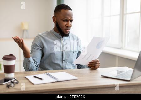 Schockierter Afrikanischer Geschäftsmann Beim Durchschauen Des Negativen Finanzberichts Im Amt Stockfoto