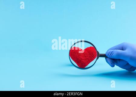 Die Herzkrankheit und Behandlungskonzept. Person mit medizinischen Latexhandschuhen Zoom in Herz-Symbol Stockfoto