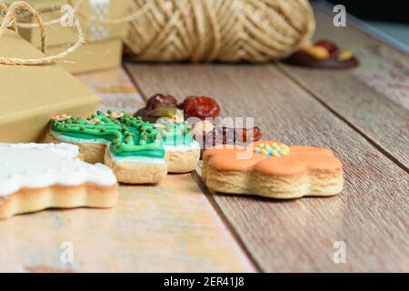 Cookies in verschiedenen Formen neben einer kleinen goldenen Box und einer Rolle Schnur (Seitenansicht). Stockfoto