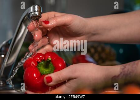 Nahaufnahme Frauen Hände waschen homegrown roten Bio-Paprika mit dem Leitungswasser. Konzept: Gesunder Lebensstil, vegan, vegetarisches Essen, Hausmannskost. Stockfoto