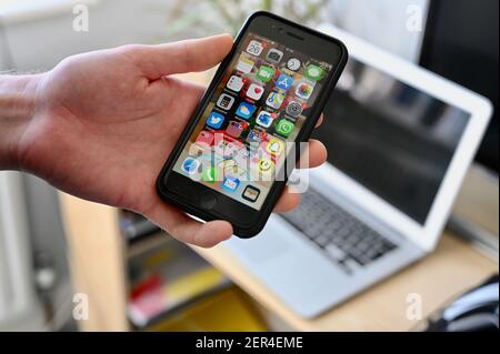 Ein junger Mann untersucht die Apps auf seinem Apple SE Handy. Stockfoto