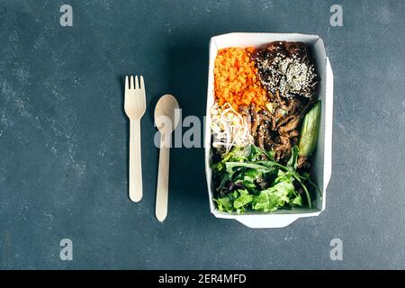 Wiederverwendbarer Verpackungsbehälter mit asiatischem Mittagessen - Rindfleisch, Nudeln, mischen grüne Blätter, Sprossen, Gemüse. Draufsicht Stockfoto