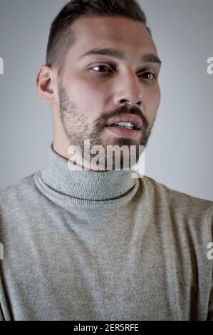 Porträt eines jungen braunhaarigen Mannes mit kurzem Bart Und einen grauen Rollkragenpullover Stockfoto