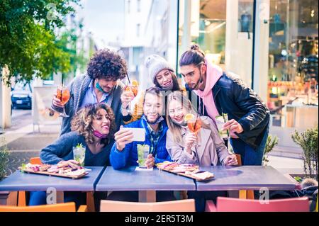 Freunde nehmen Selfie draußen an der Cocktailbar - Neu normal Lifestyle-Konzept mit jungen Leuten, die gemeinsam im Restaurant Spaß haben Mit Gesichtsmasken Stockfoto