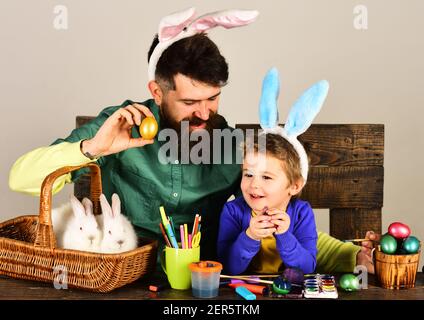 Osterfamilie hält Korb mit bemalten Eiern. Hasenohren und Hasenohren Design. Stockfoto