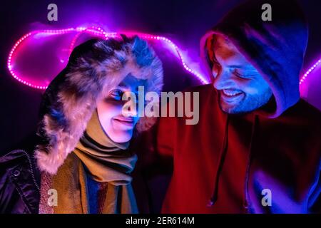 Happy arabisch muslimische Geschwister mit farbigen Lichtern hinter ihnen in Dunkles Zimmer Stockfoto