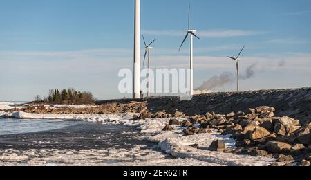 Windturbinen an der schwedischen Ostsee und ein Steinsteg, der das Meer vor dem Land schützt. 2021. Februar 28 Stockfoto