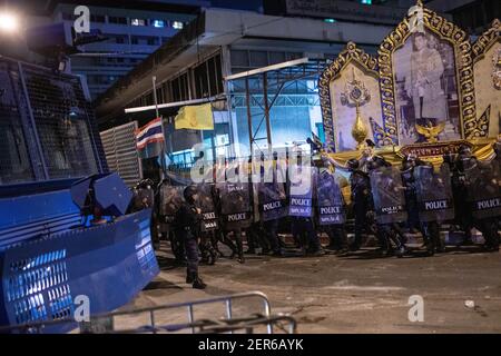 Neben einem Porträt des thailändischen Königs Maha Vajiralongkorn während einer Anti-Regierungsdemonstration in Bangkok stehen die Bereitschaftspolizisten hinter ihren Schilden.Tausende von prodemokratischen Demonstranten versammelten sich in der Vibhavadi Rangsit Road vor dem Infanterie-Regiment 1st in der Nähe des Premierministers und forderten den Rücktritt des thailändischen Premierministers und Die Reform der Monarchie in Bangkok, Thailand. Die Demonstranten verurteilten auch die Anwendung des ‘Lese majeste Gesetz' unter dem Abschnitt 112 des Strafgesetzbuches. Der von ‘FreeYouth' organisierte Protest endete mit mehreren Zusammenstößen, dem Einsatz von Wasserwerfern, Tränengas Stockfoto