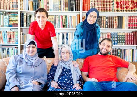Glückliche arabische muslimische Familie sitzt zusammen auf der Couch und lächelt Stockfoto