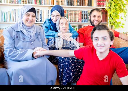 Glückliche arabische muslimische Familie sitzt zusammen auf der Couch und lächelt Stockfoto