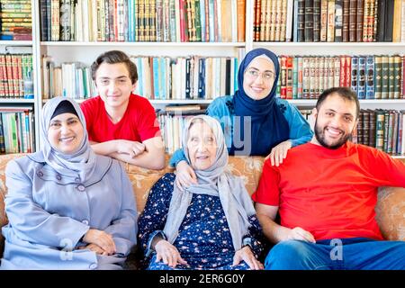 Glückliche arabische muslimische Familie sitzt zusammen auf der Couch und lächelt Stockfoto