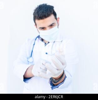 Arabischer Arzt trägt Handschuhe, um ihn selbst vor Infektionen zu schützen Stockfoto