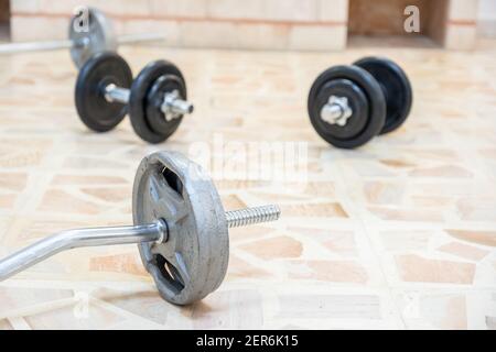 Langhantel und Kurzhanteln auf dem Boden für das Heimtraining Stockfoto