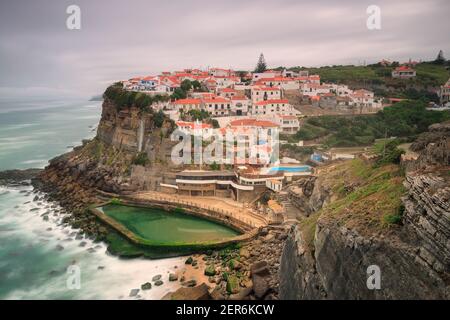 Malerisches Dorf Azenhas do Mar. Weiße Ferienhäuser am Rande einer Klippe mit einem Strand und Pool unten. Wahrzeichen in der Nähe von Lissabon, Portugal, Stockfoto