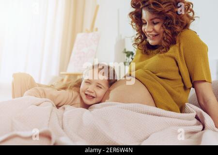 Schwangere Mutter spielt mit ihrer Tochter. Familienkonzept, Freude und Schwangerschaft Stockfoto