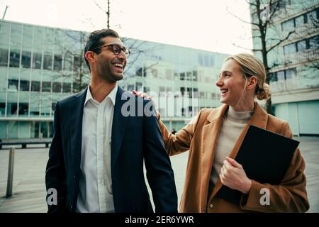 Kaukasische Geschäftsmann und Frau lächelnd zu Fuß durch die Stadt halten Notizbuch Stockfoto