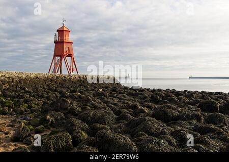 Die leuchtend rot bemalte Herde Groyne Lighhouse steht in der Mündung des Flusses Tyne in Littlehaven, South Shields in Tyne und tragen. Stockfoto